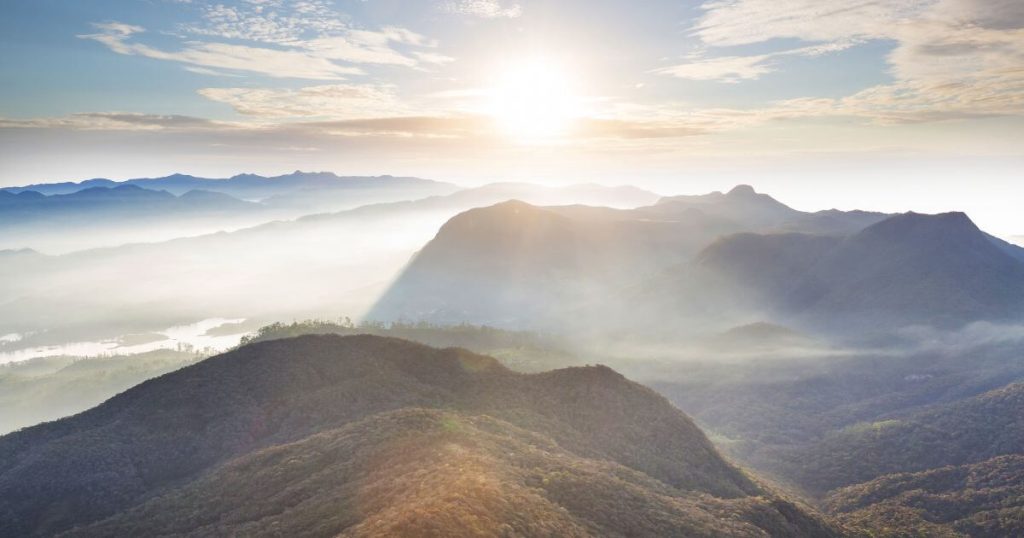 這張圖片展示了斯里蘭卡著名的亞當峰日出,山巒疊嶂,晨光照耀,霧氣繚繞,呈現出一幅壯麗的自然景觀。