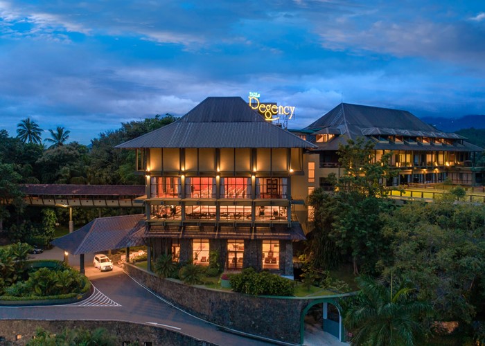 這張圖片展示了位於斯里蘭卡康提的Earl's Regency酒店，該酒店被群山環繞，建築設計融入自然景觀。建築物在夜晚燈光的映照下顯得格外迷人，是該地區知名的高檔住宿選擇之一。