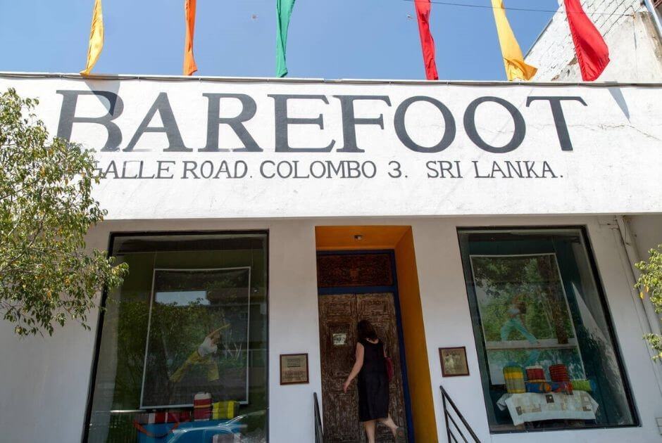 該圖片展示了斯里蘭卡科倫坡的 Barefoot 紡織店正門,位於 Galle Road,店面設計簡約,招牌上清晰標示「BAREFOOT」,並懸掛著鮮艷的旗幟。顧客進入店內,體現該店的熱門購物地點特色。