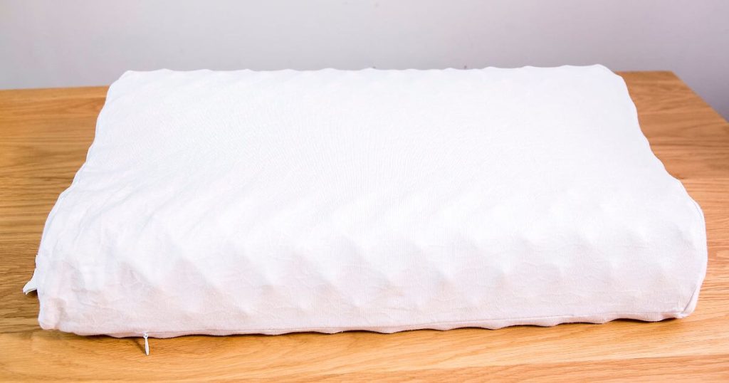 一個平放在木製桌上的白色乳膠枕頭，展現了其簡約而自然的質感。