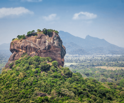 錫吉里亞獅子岩高聳於綠意盎然的森林中，周圍環繞著遼闊的草原與遠處的山脈，是斯里蘭卡最具歷史和考古價值的地標。